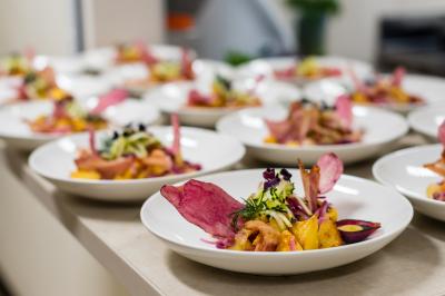 Un serveur portant un plateau avec des flûtes de champagne lors d'un événement en extérieur sous des arbres.