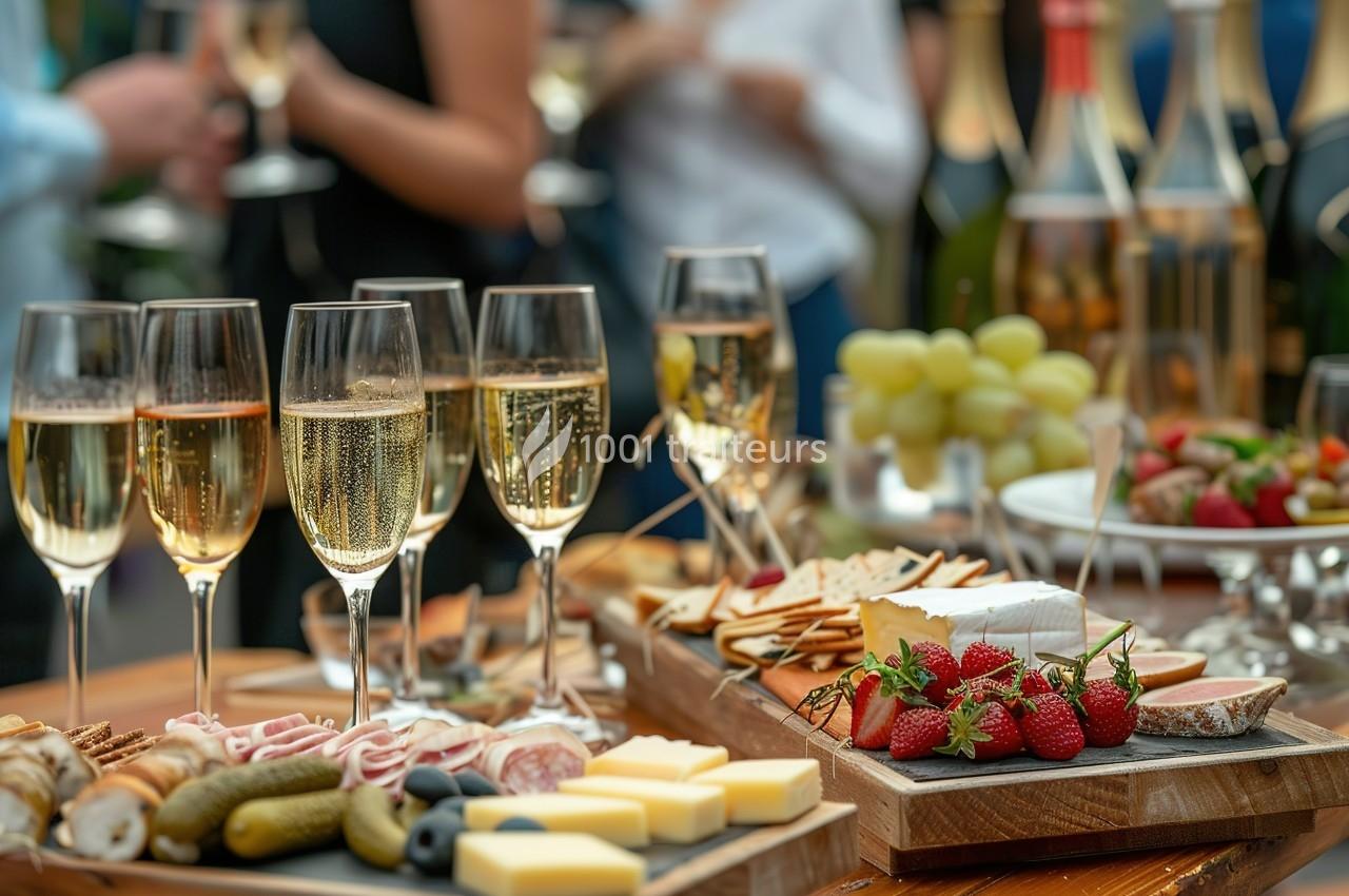 Table garnie de coupes de champagne, fromages, fruits, charcuteries et amuse-bouches lors d'un événement festif.