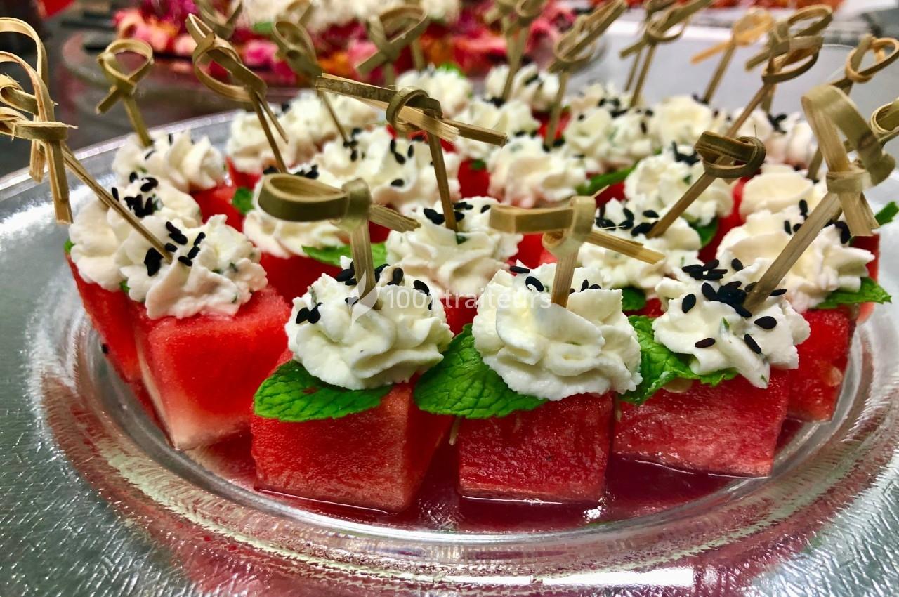 Carrés de pastèque garnis de crème, feuilles de menthe et graines de sésame, présentés avec des piques en bois.