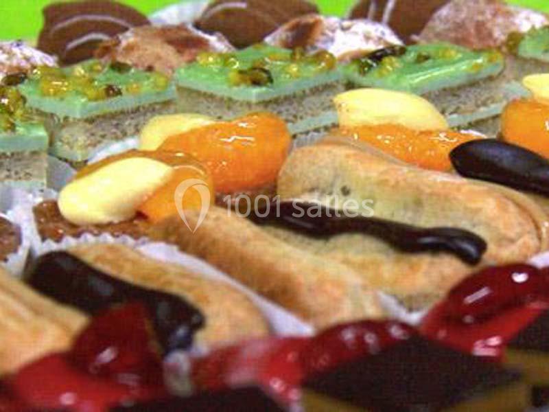 Assortiment de pâtisseries variées avec glaçages colorés et fruits, disposées sur un plateau.
