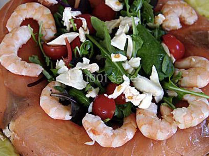 Assiette garnie de saumon fumé, crevettes, roquette, tomates cerises et morceaux de fromage.