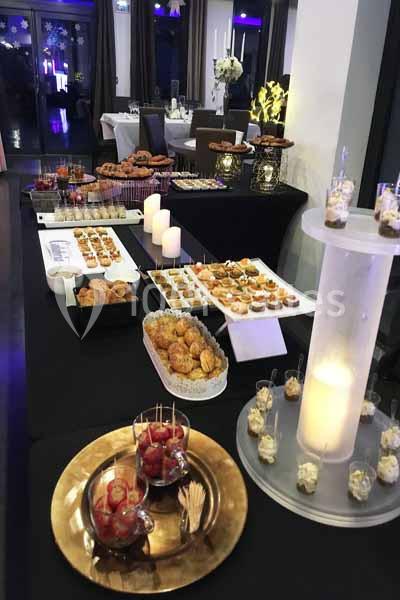Buffet de réception avec divers plats salés et sucrés présentés sur des tables décorées de bougies et de fleurs.