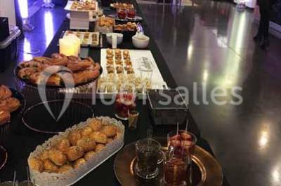 Centre de table floral avec roses et magnolias, bouteille de vin, numéro de table et décorations sur une nappe blanche.