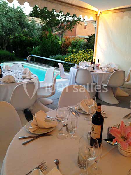 Tables élégamment dressées sous une tente, près d'une piscine entourée de végétation.