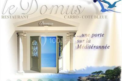 Centre de table floral avec roses et magnolias, bouteille de vin, numéro de table et décorations sur une nappe blanche.