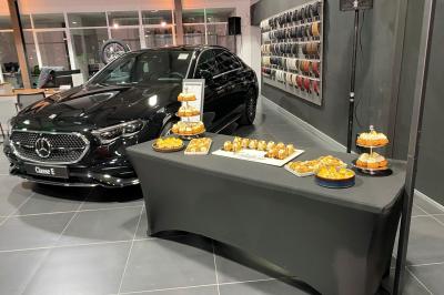 Centre de table floral avec roses et magnolias, bouteille de vin, numéro de table et décorations sur une nappe blanche.