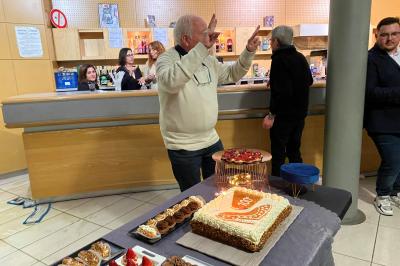 Centre de table floral avec roses et magnolias, bouteille de vin, numéro de table et décorations sur une nappe blanche.
