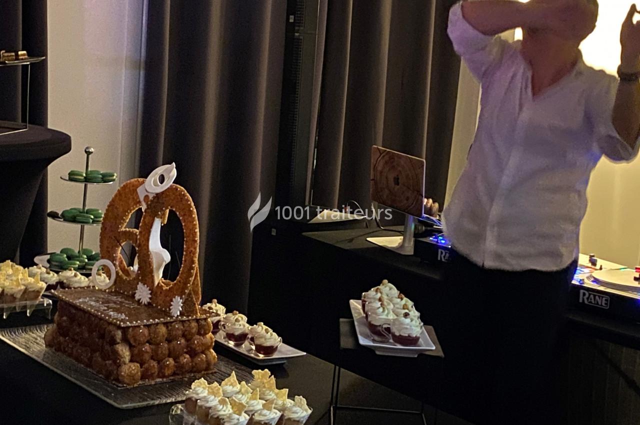 Une pièce montée en choux et divers desserts présentés sur une table lors d'une réception en intérieur.