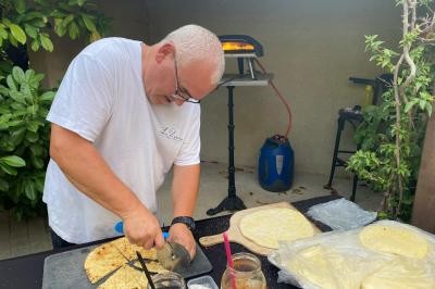 Centre de table floral avec roses et magnolias, bouteille de vin, numéro de table et décorations sur une nappe blanche.