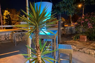 Centre de table floral avec roses et magnolias, bouteille de vin, numéro de table et décorations sur une nappe blanche.