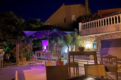 Centre de table floral avec roses et magnolias, bouteille de vin, numéro de table et décorations sur une nappe blanche.