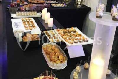 Centre de table floral avec roses et magnolias, bouteille de vin, numéro de table et décorations sur une nappe blanche.