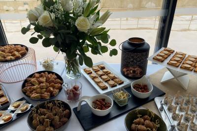 Centre de table floral avec roses et magnolias, bouteille de vin, numéro de table et décorations sur une nappe blanche.