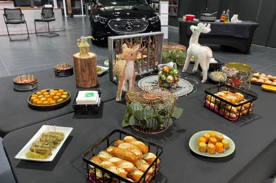Centre de table floral avec roses et magnolias, bouteille de vin, numéro de table et décorations sur une nappe blanche.