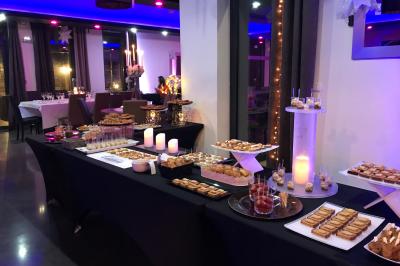 Centre de table floral avec roses et magnolias, bouteille de vin, numéro de table et décorations sur une nappe blanche.