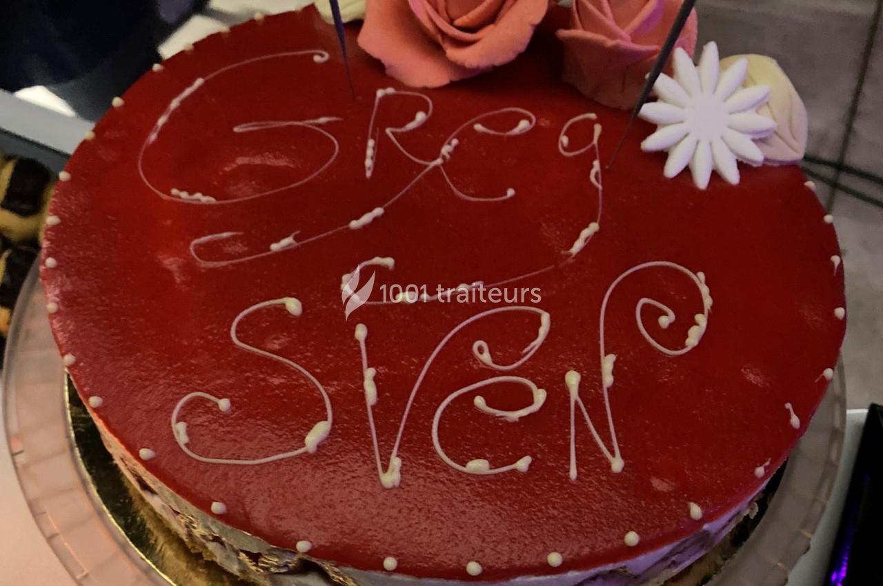 Gâteau rouge décoré de roses en pâte à sucre, avec les prénoms ’Greg’ et ’Sven’ écrits en glaçage blanc.