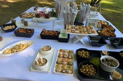 Centre de table floral avec roses et magnolias, bouteille de vin, numéro de table et décorations sur une nappe blanche.