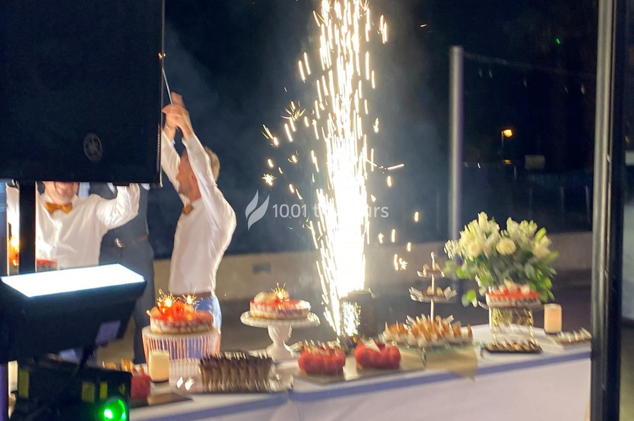 Un buffet décoré avec des desserts et des fleurs, accompagné d'une fontaine lumineuse en arrière-plan.