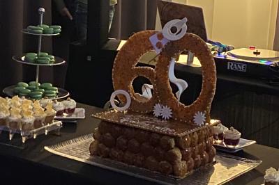 Centre de table floral avec roses et magnolias, bouteille de vin, numéro de table et décorations sur une nappe blanche.