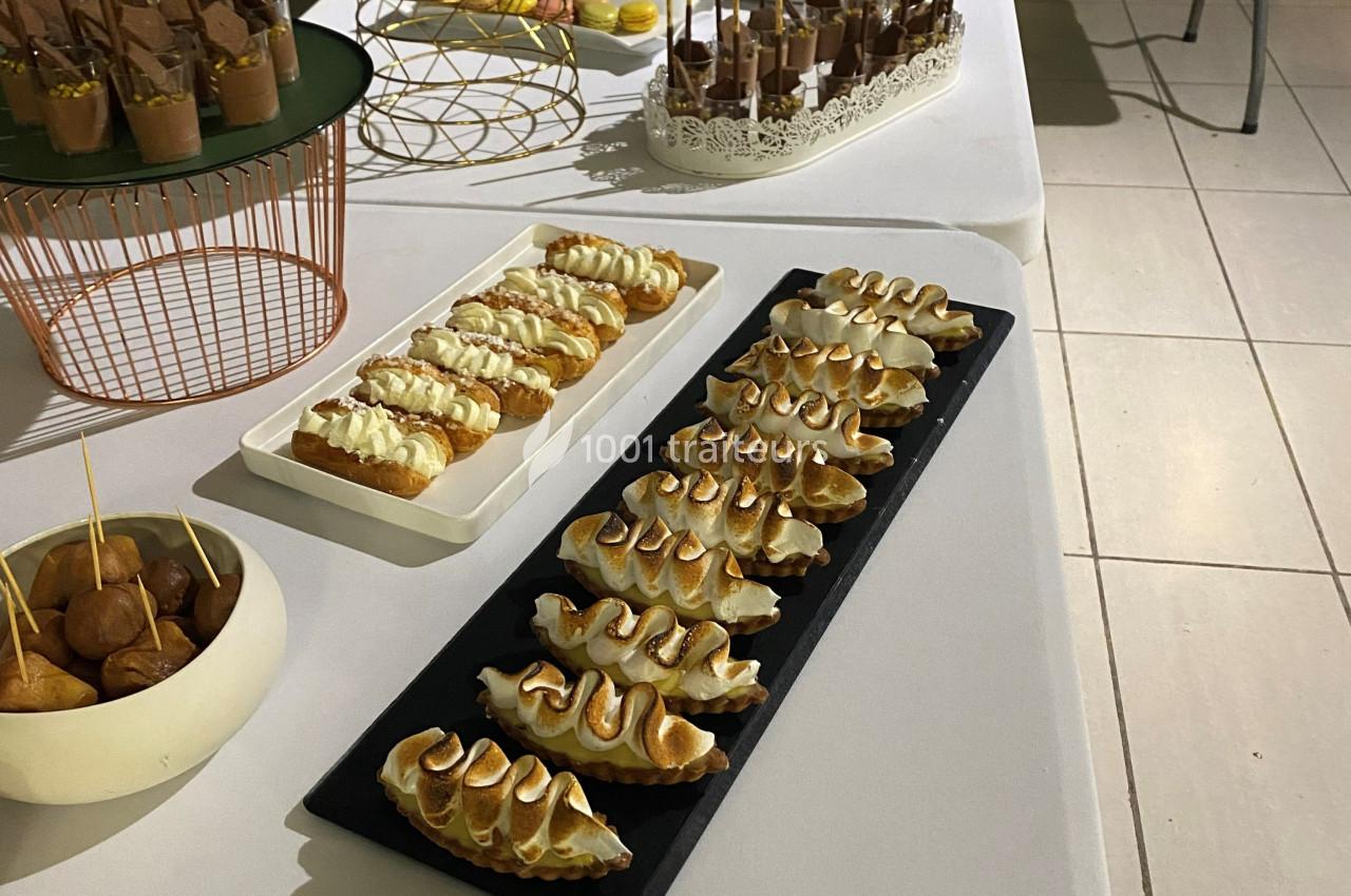Plateau de pâtisseries variées, dont des éclairs et des desserts meringués, disposés sur une table blanche.