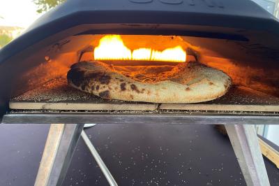 Centre de table floral avec roses et magnolias, bouteille de vin, numéro de table et décorations sur une nappe blanche.