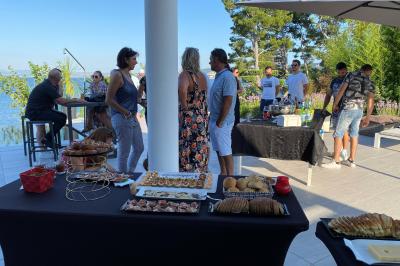 Centre de table floral avec roses et magnolias, bouteille de vin, numéro de table et décorations sur une nappe blanche.