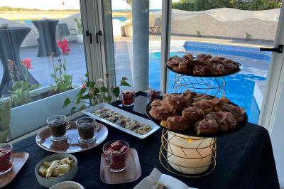 Centre de table floral avec roses et magnolias, bouteille de vin, numéro de table et décorations sur une nappe blanche.