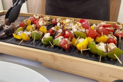 Groupe de personnes rassemblées en extérieur sous des arbres, près d'une table garnie de plats variés.