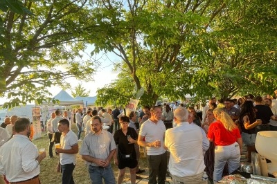 Groupe de personnes rassemblées en extérieur sous des arbres, près d'une table garnie de plats variés.