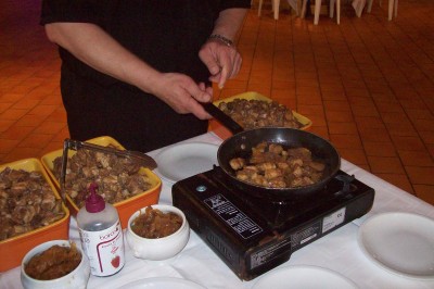 Chambre mansardée avec deux lits simples, parquet clair, poutres apparentes et lumière naturelle provenant d'un velux.