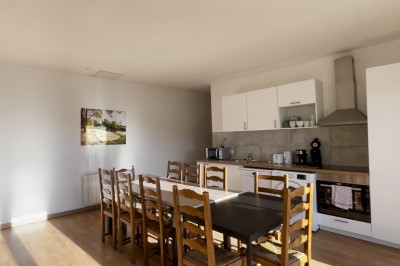 Chambre mansardée avec deux lits simples, parquet clair, poutres apparentes et lumière naturelle provenant d'un velux.