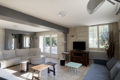 Chambre mansardée avec deux lits simples, parquet clair, poutres apparentes et lumière naturelle provenant d'un velux.