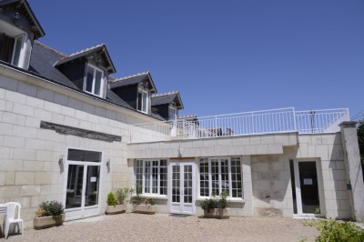 Chambre mansardée avec deux lits simples, parquet clair, poutres apparentes et lumière naturelle provenant d'un velux.
