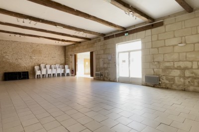 Chambre mansardée avec deux lits simples, parquet clair, poutres apparentes et lumière naturelle provenant d'un velux.