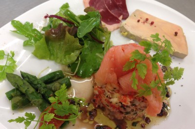 Chambre mansardée avec deux lits simples, parquet clair, poutres apparentes et lumière naturelle provenant d'un velux.