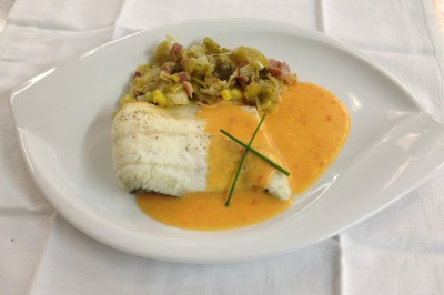 Chambre mansardée avec deux lits simples, parquet clair, poutres apparentes et lumière naturelle provenant d'un velux.