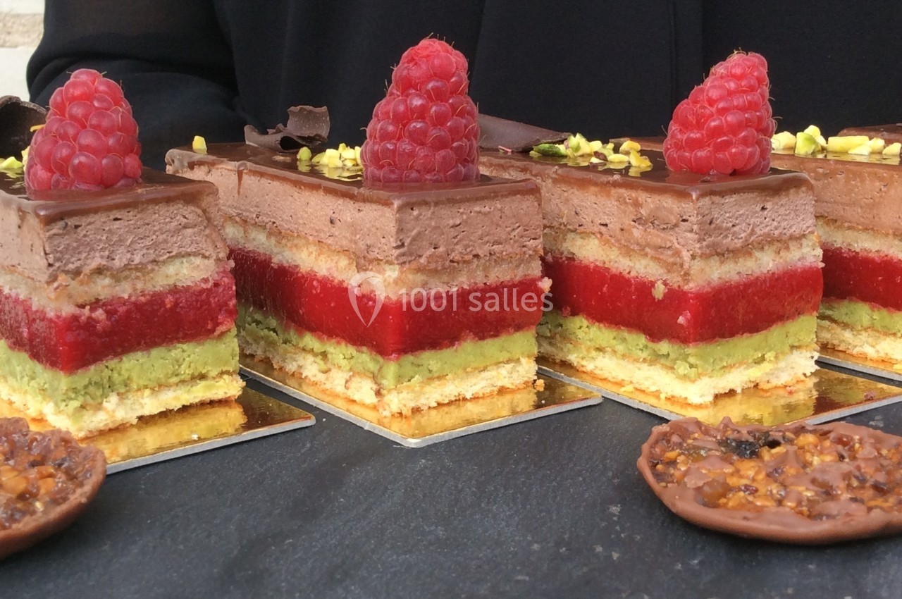 Gâteaux à étages avec mousse au chocolat, gelée rouge, crème verte, décorés de framboises et éclats de pistache.