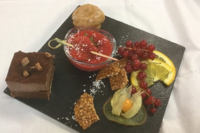 Chambre mansardée avec deux lits simples, parquet clair, poutres apparentes et lumière naturelle provenant d'un velux.