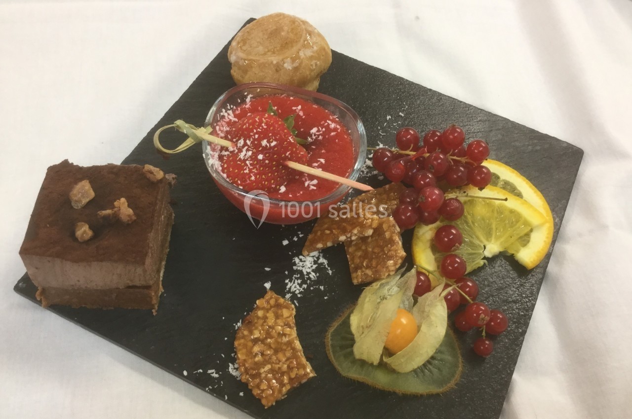 Assortiment de desserts sur une ardoise comprenant mousse au chocolat, sorbet, fruits frais et nougatine.