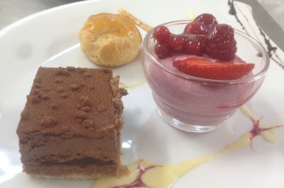 Chambre mansardée avec deux lits simples, parquet clair, poutres apparentes et lumière naturelle provenant d'un velux.