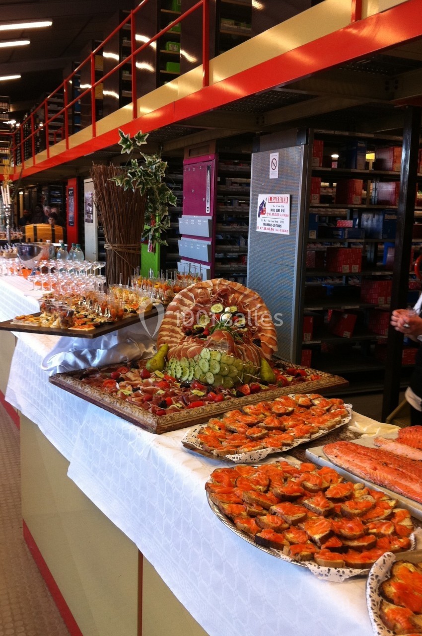 Buffet avec assortiment de fruits de mer, charcuteries, pains et verrines disposés sur une table dans un espace intérieur.