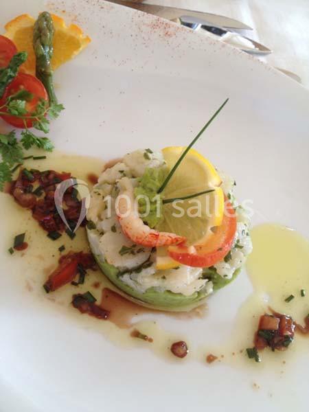 Tartare de poisson blanc sur lit d'avocat, décoré de citron, tomate, ciboulette et vinaigrette.