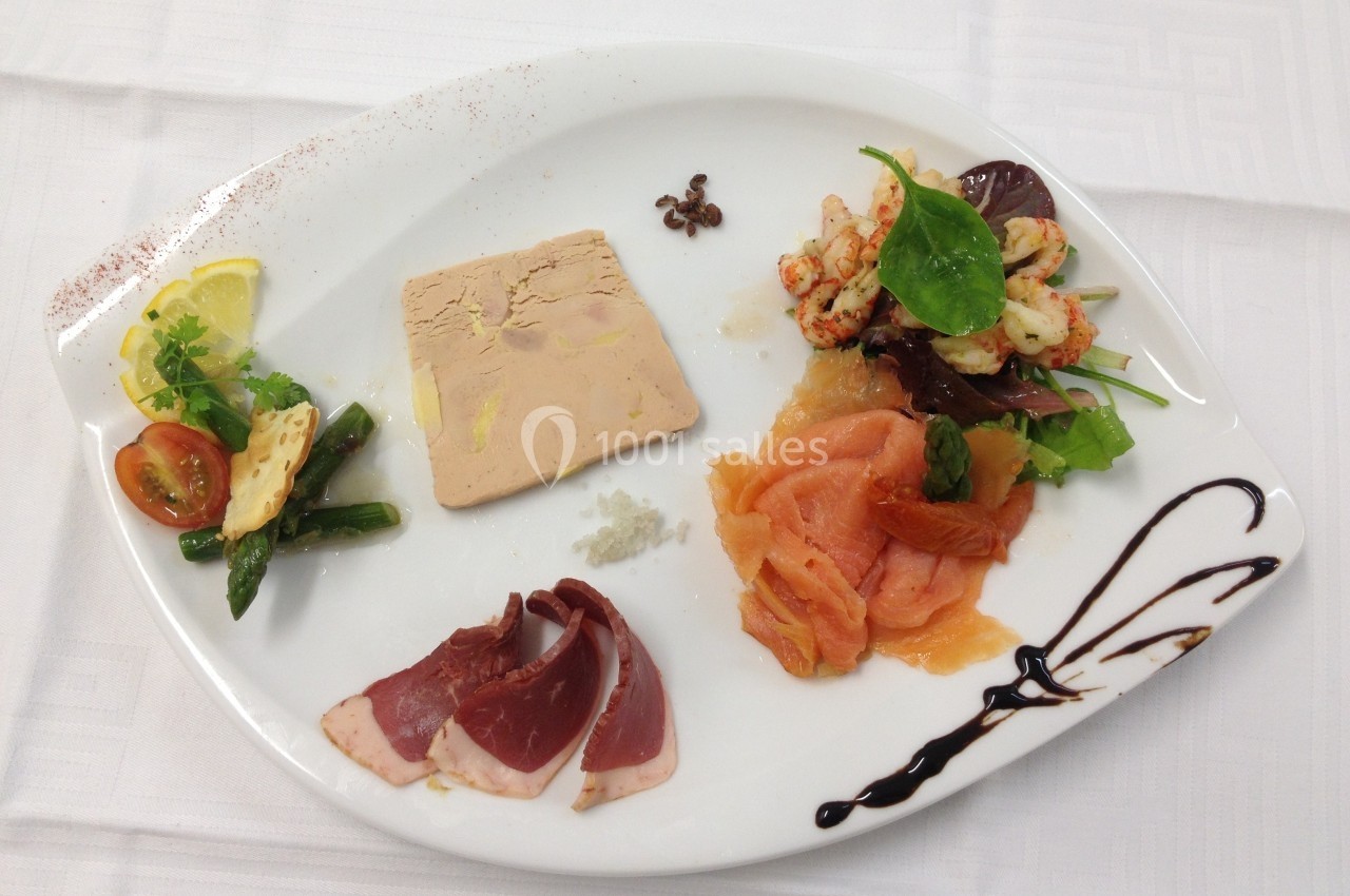 Assiette composée de foie gras, saumon fumé, magret de canard, crevettes, légumes et décorations culinaires.