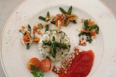 Salle avec des rangées de chaises en plastique blanc disposées face à une scène lumineuse dans un espace aux murs clairs.