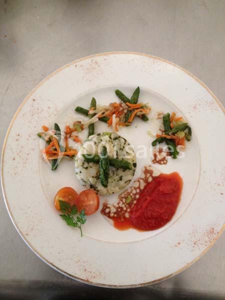 Assiette gastronomique avec riz aux herbes, asperges, légumes sautés, purée de tomate et décoration de tomates cerises.