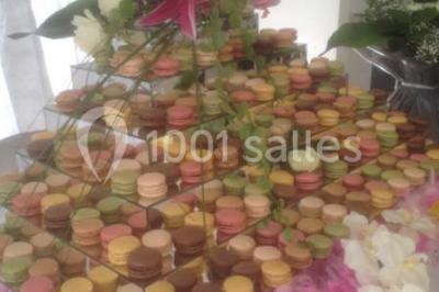 Salle avec des rangées de chaises en plastique blanc disposées face à une scène lumineuse dans un espace aux murs clairs.