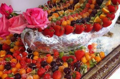 Salle avec des rangées de chaises en plastique blanc disposées face à une scène lumineuse dans un espace aux murs clairs.