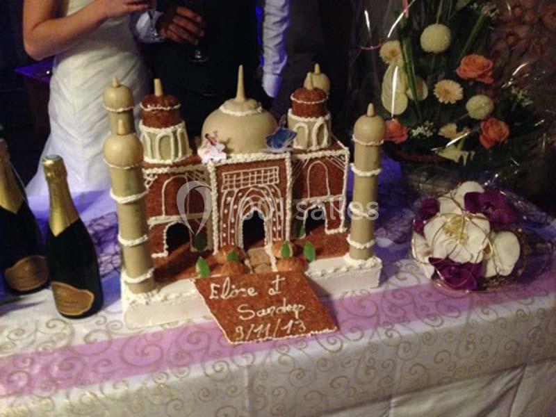 Maquette en pain d'épices représentant le Taj Mahal, posée sur une table décorée avec des fleurs et des bouteilles.
