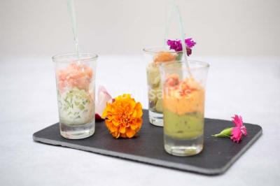 Un kiosque blanc au bord d'un étang avec une fontaine, entouré d'arbres et d'une réception en arrière-plan.