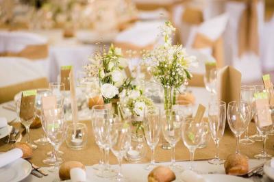Un kiosque blanc au bord d'un étang avec une fontaine, entouré d'arbres et d'une réception en arrière-plan.